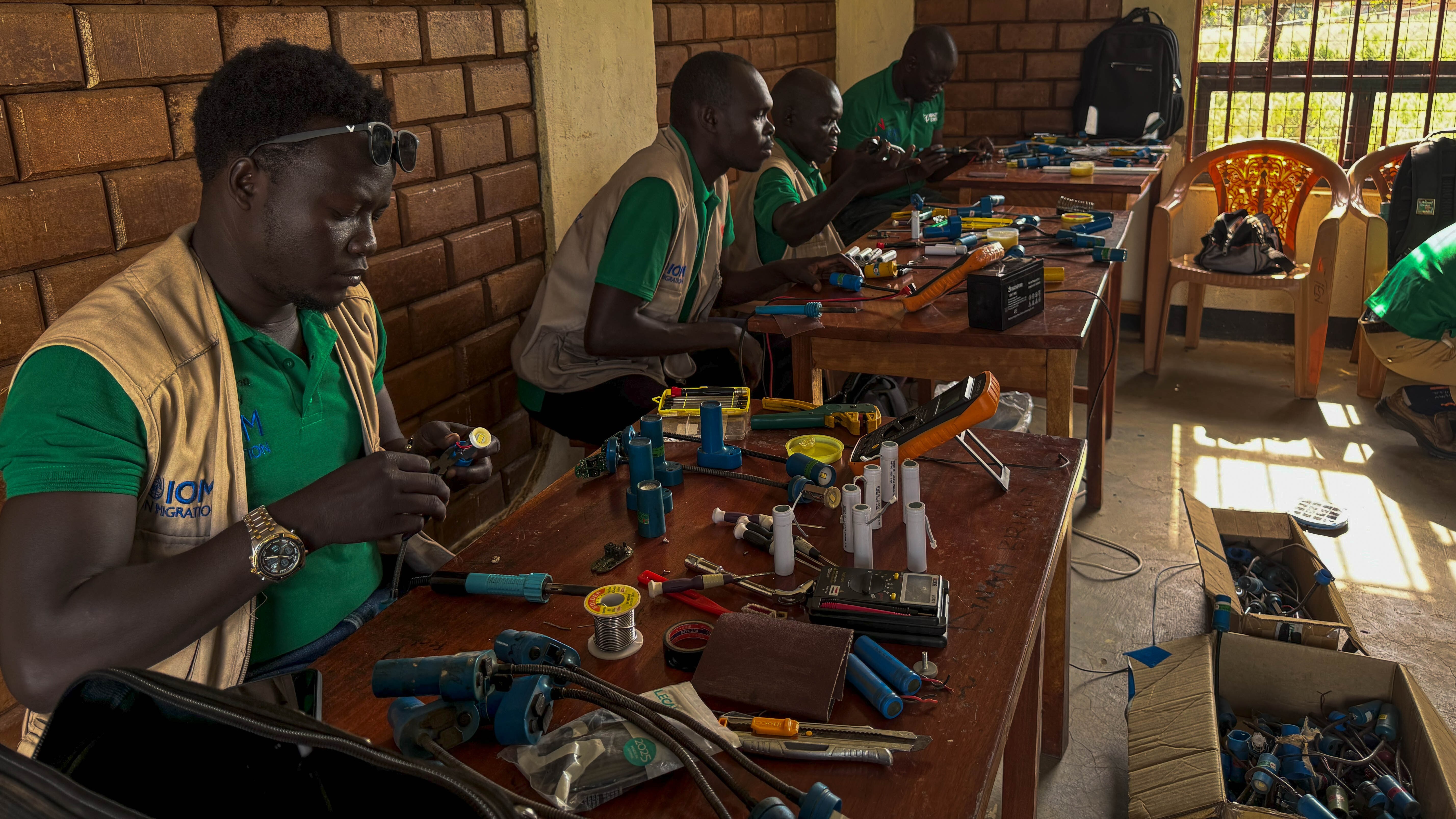 Technicians trained through BRIGHT's solar lamp Repair Program busy at work at the repair centre in Bidibidi (© IOM)