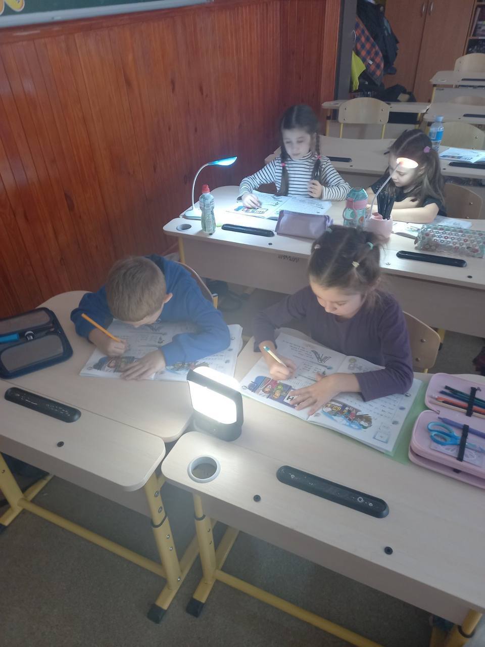 Two students share a Sol Mid Capacity solar lamp as they work together in class.