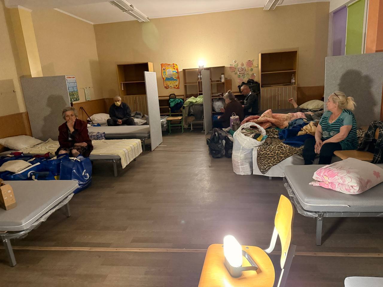 Evacuees gather in a room at the Lozova Transit Centre in southern Kharkiv, illuminated by the soft light of two Sol solar lamps.