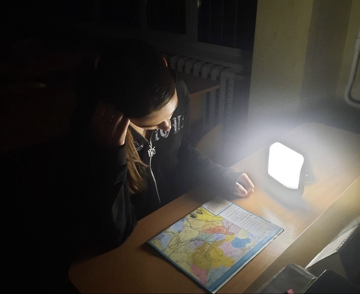 A student in Kyiv uses the BRIGHT Sol Mid Capacity solar lamp to study a map.