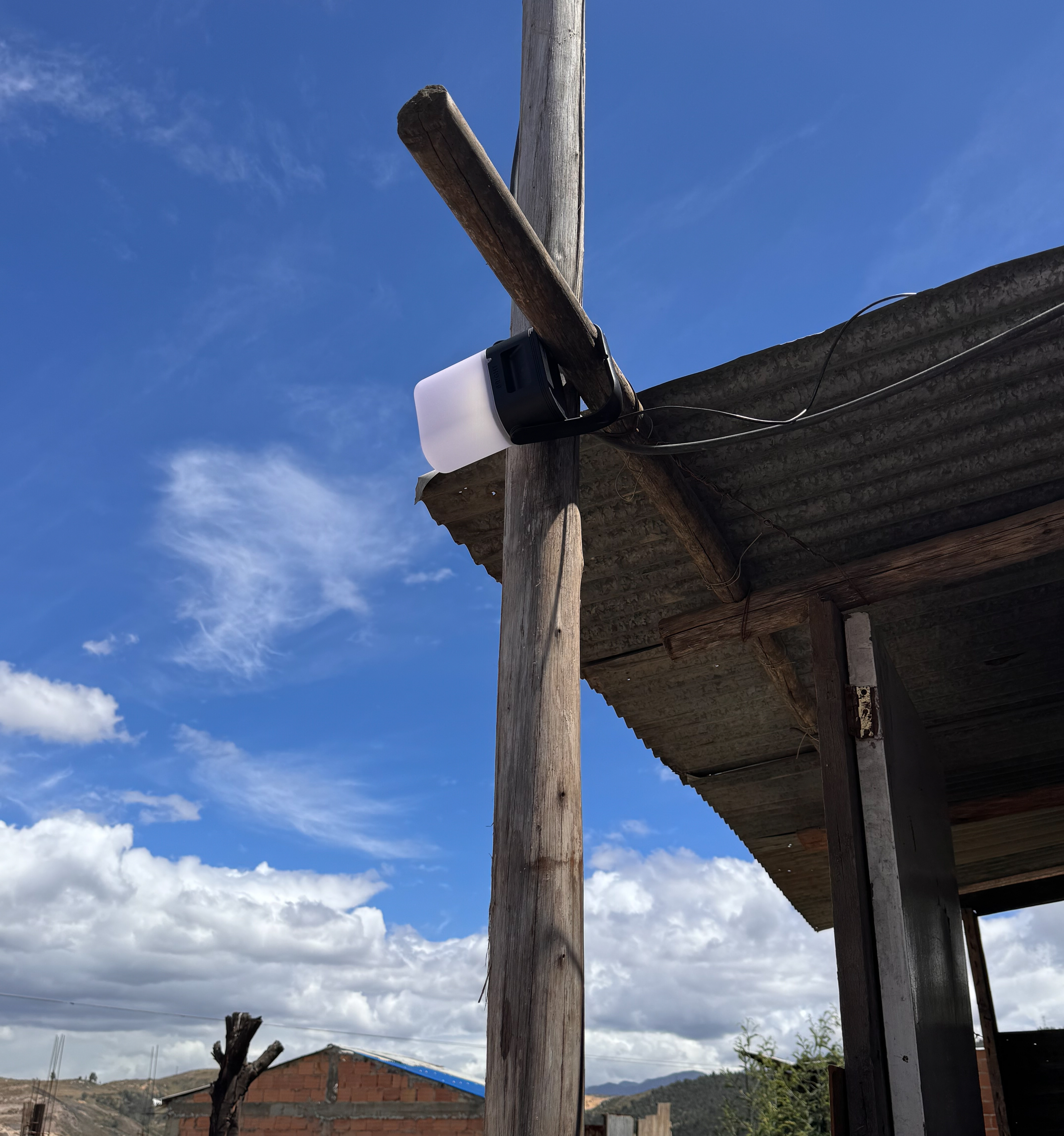 A group of TECHO Colombia representatives testing a Sol Mid Capacity solar lamp outdoors near shelters to provide external lighting.